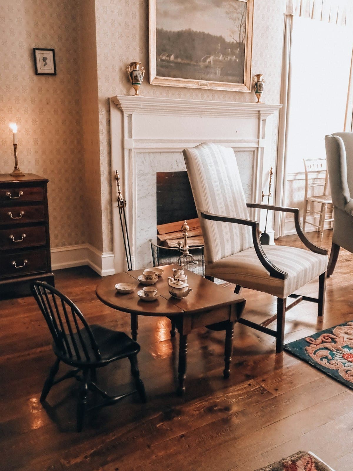 A quiet sitting room with a fireplace, armchair and tea things on a small table